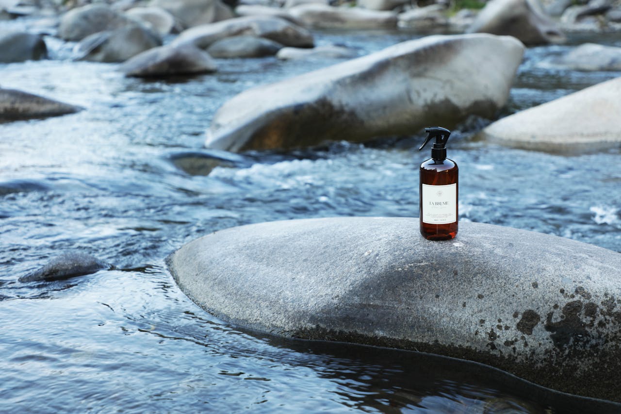 Spray bottle positioned on river rock in natural Chilean landscape.